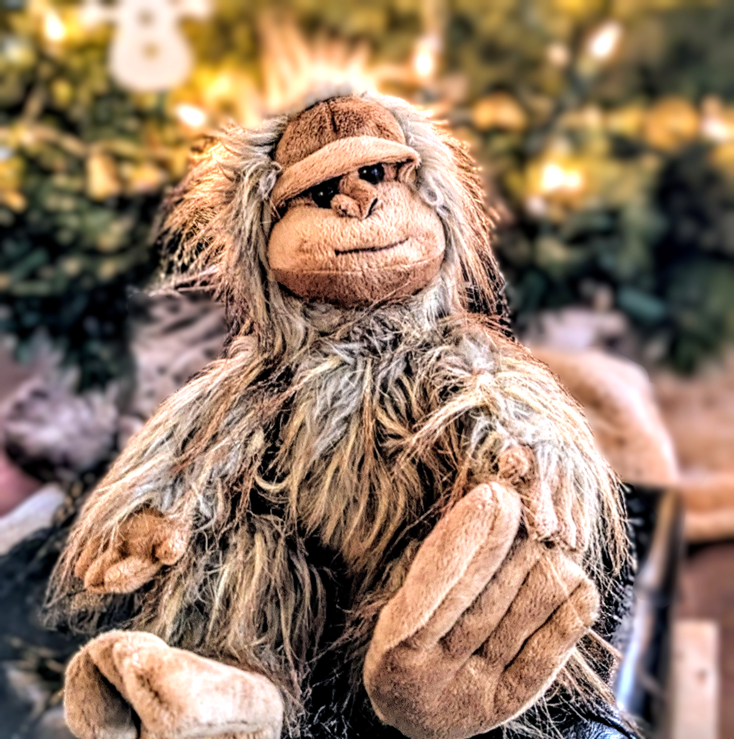 Plush toy resembling a creature with long hair against a blurred Christmas tree background