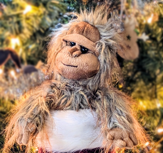 Stuffed animal with a furry texture in front of a blurred Christmas tree background
